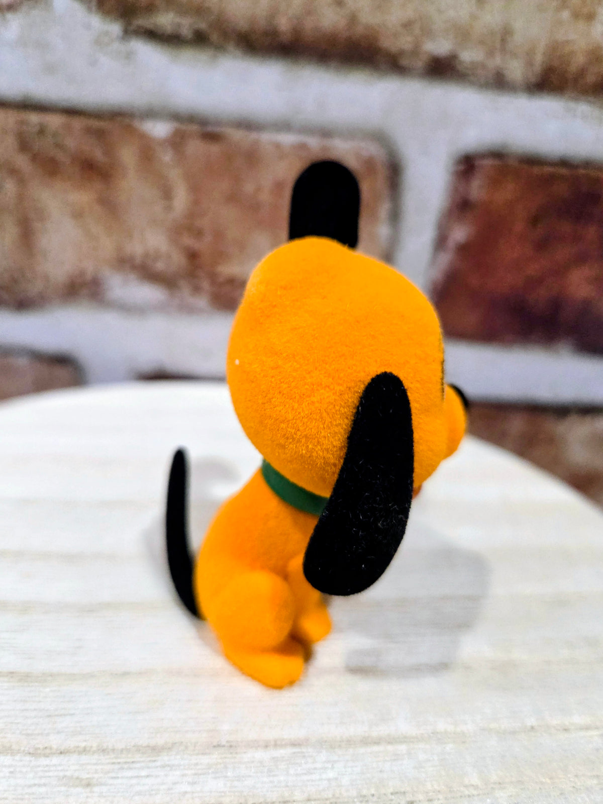 Flocked Pluto mini figure rear view, orange plush with black tail and green collar