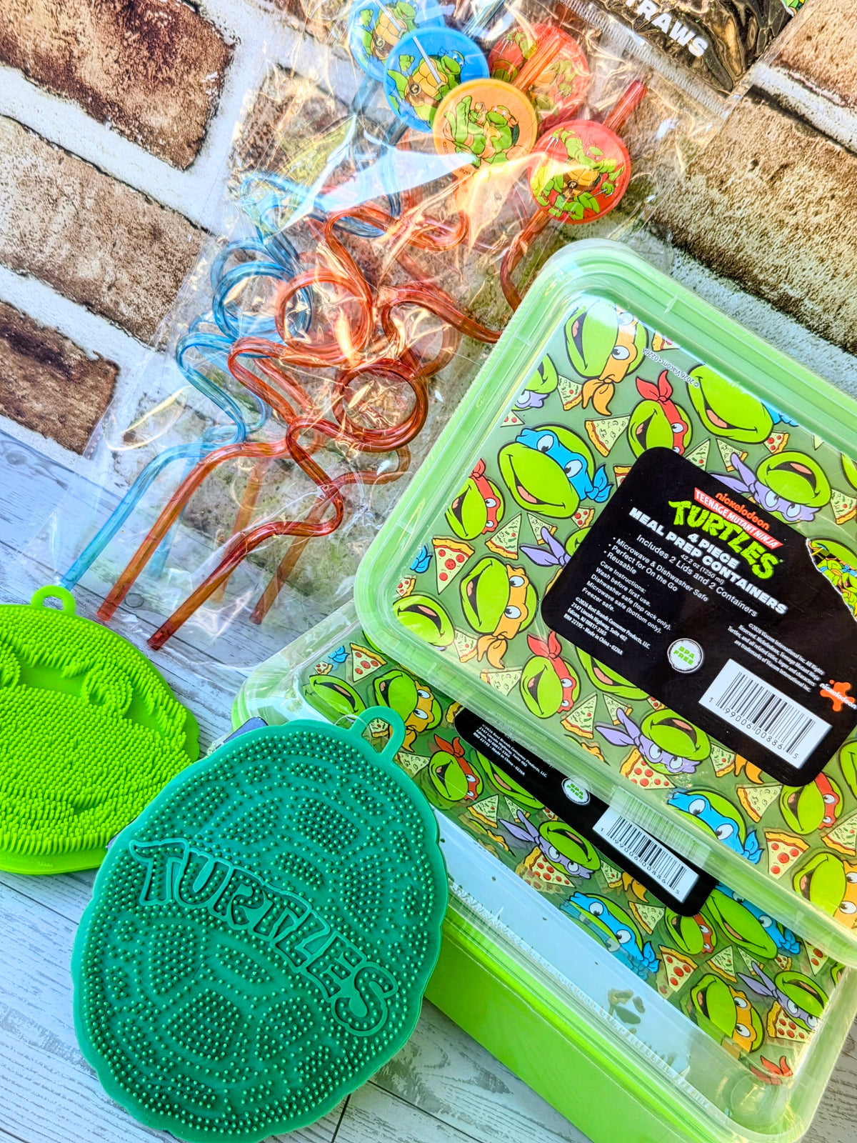 Green silicone scrubber pad beside Turtle-pattern meal prep containers in gift set