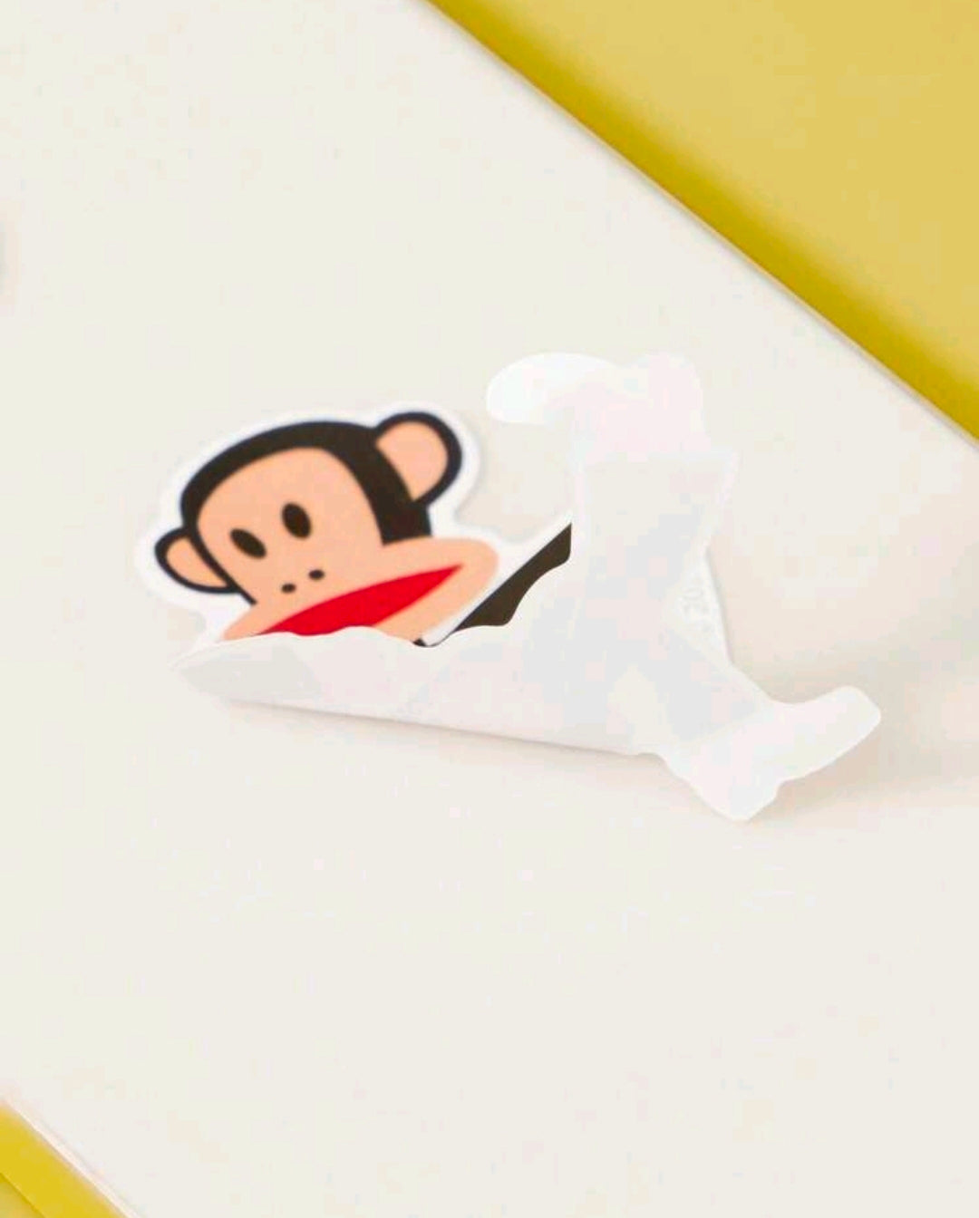 Vinyl cartoon monkey sticker with red scarf, black cap, and peach face