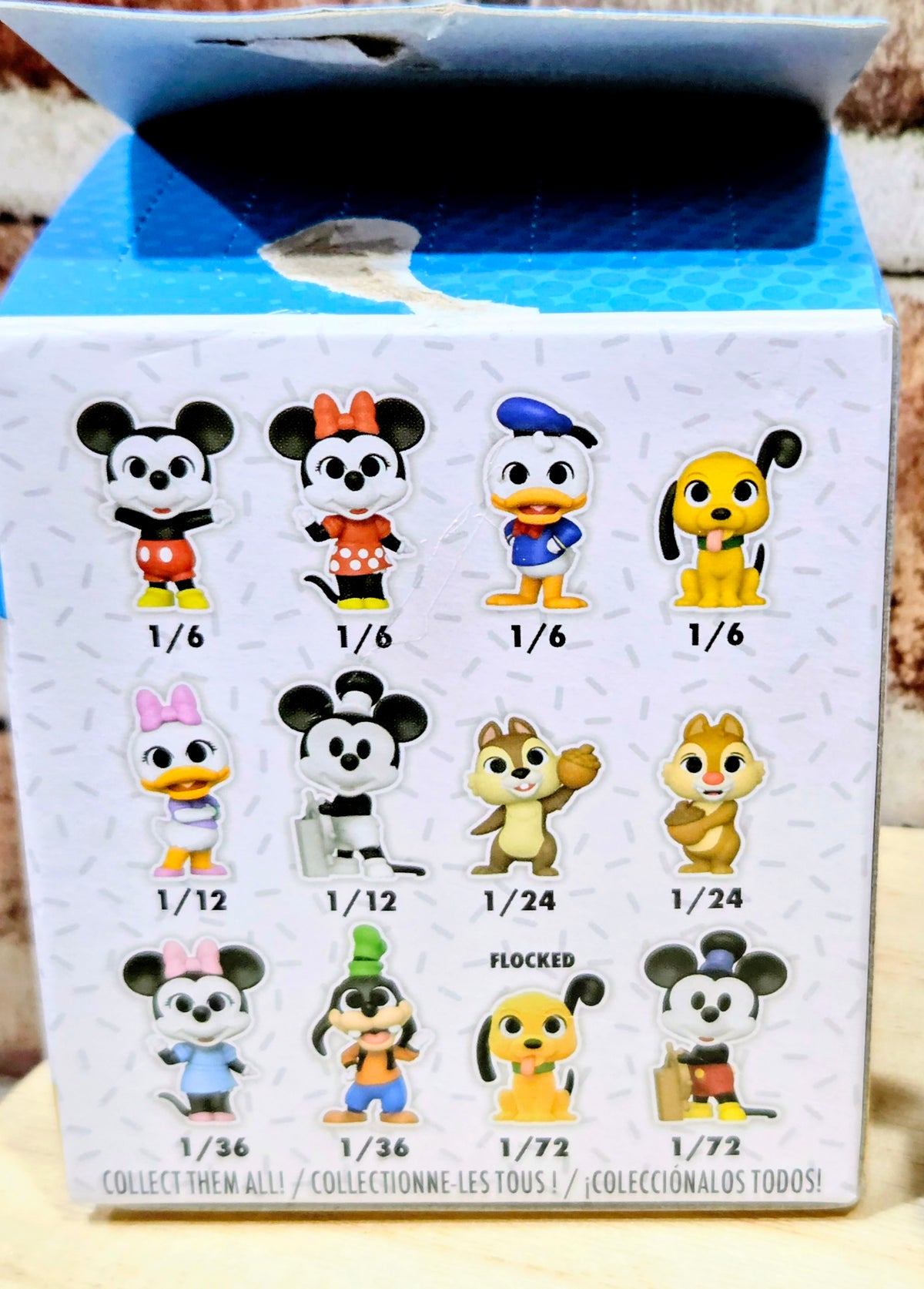 Vinyl mystery figure display box with character lineup and scale icons.