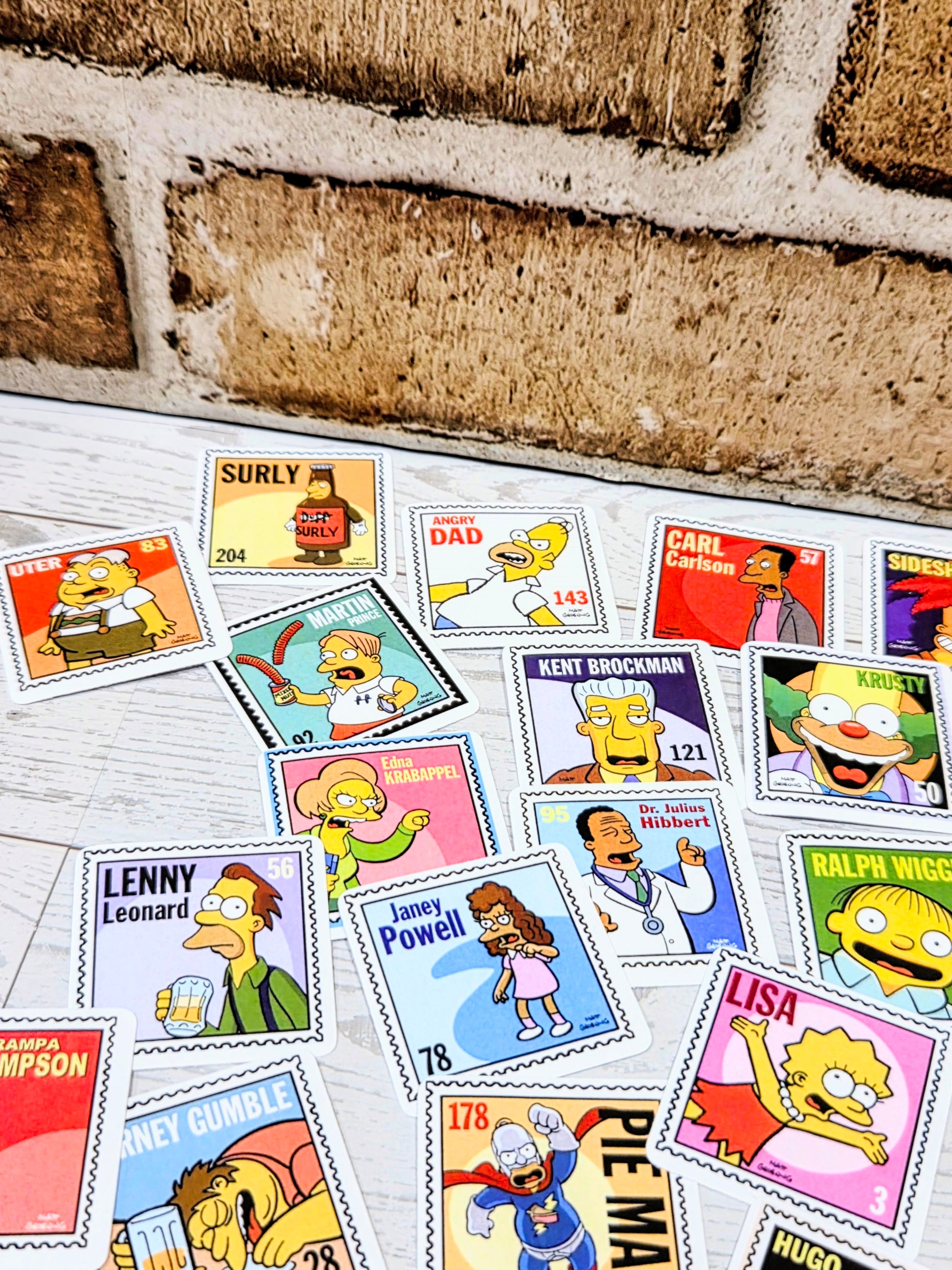 Close-up of Simpsons postage-stamp style decals with character portraits arranged on light surface