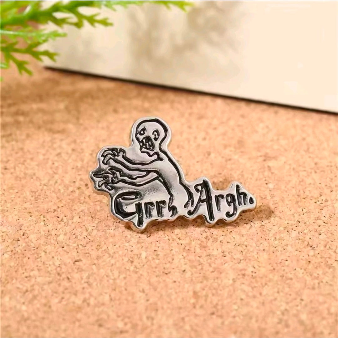 Grr Argh enamel lapel pin on cork board, silver-tone figure and “Grr Argh” text