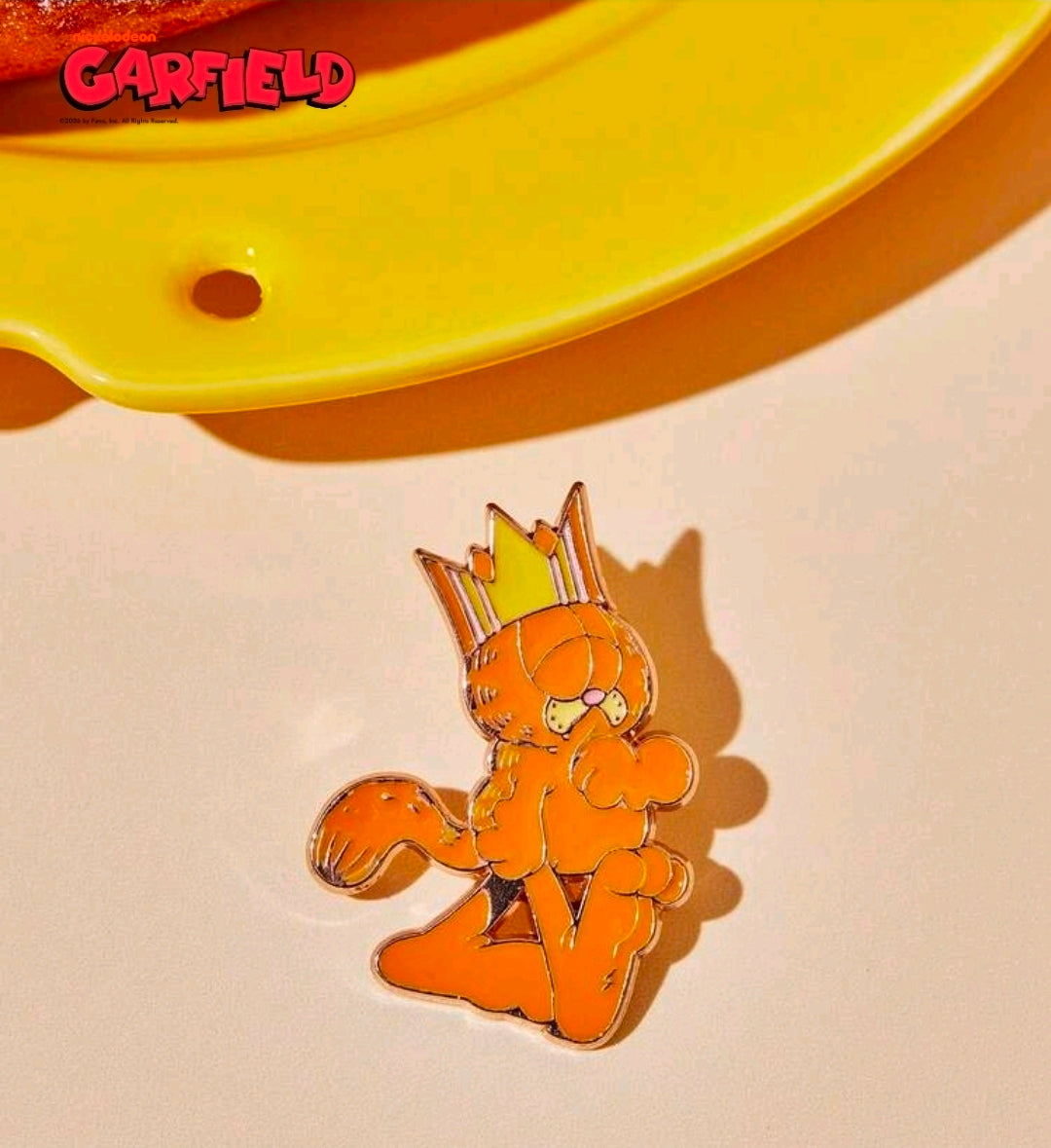 Enamel character pin of Garfield wearing a crown, gold-outlined, seated