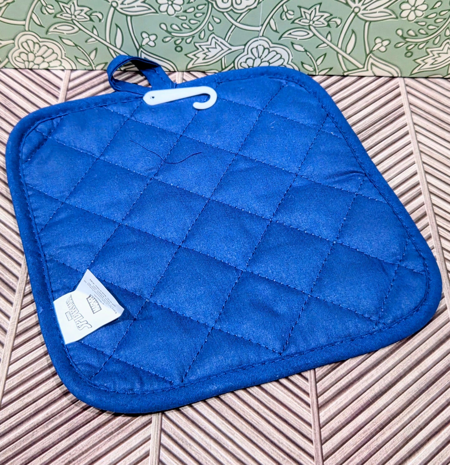 Blue quilted pot holder with hanging loop on square backing