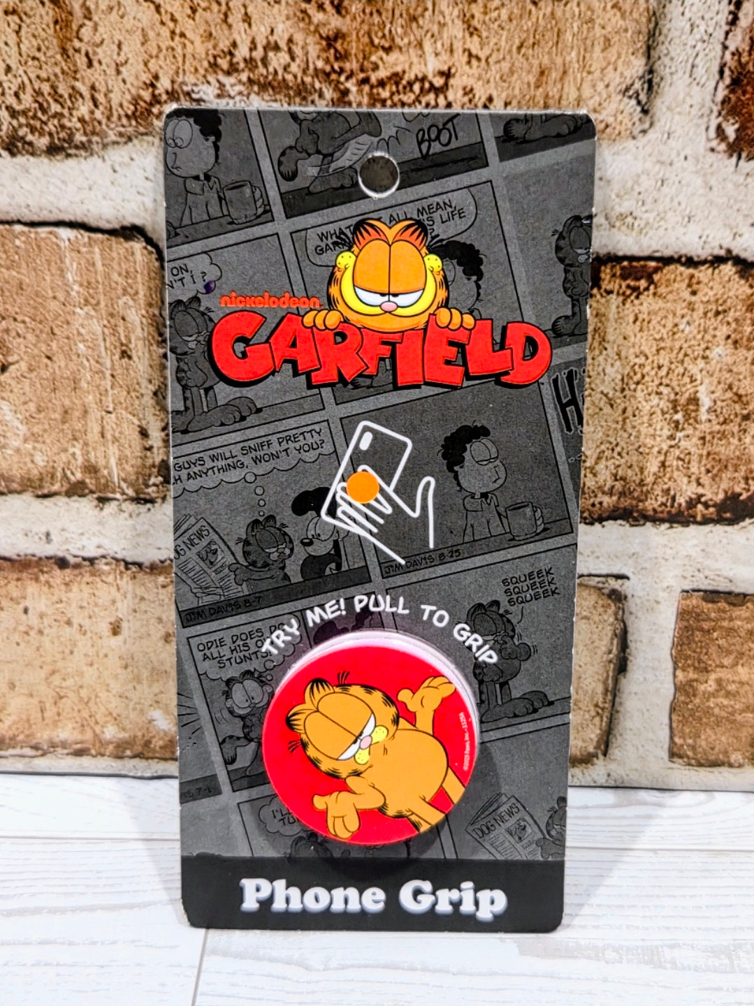 Garfield phone grip holder with black packaging and Garfield graphic, pop socket front.