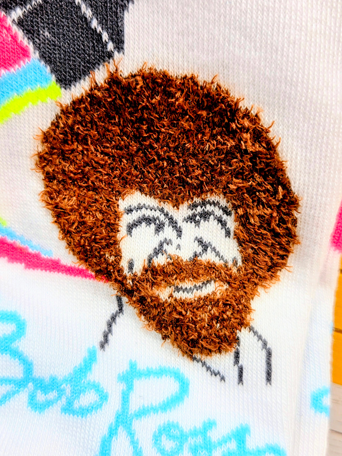 Close-up of white crew sock showing brown dog face graphic and blue/pink details