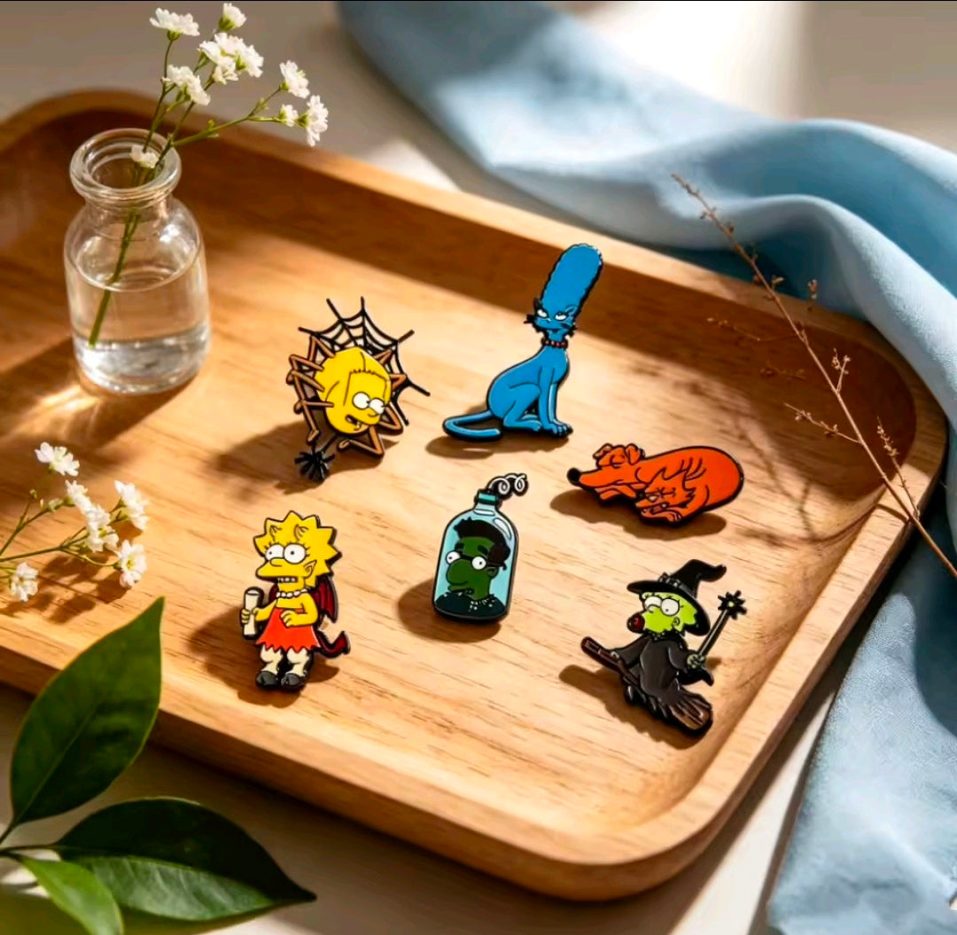 Assorted Halloween enamel pins on a wooden tray with decorative items