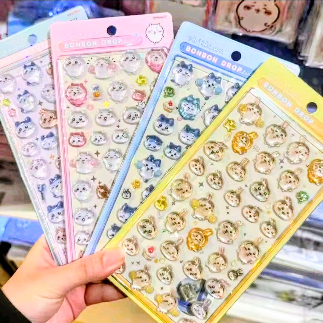 Hand holding Chiikawa Bon Bon Drop 3D acrylic sticker sheets in pink, blue, and yellow