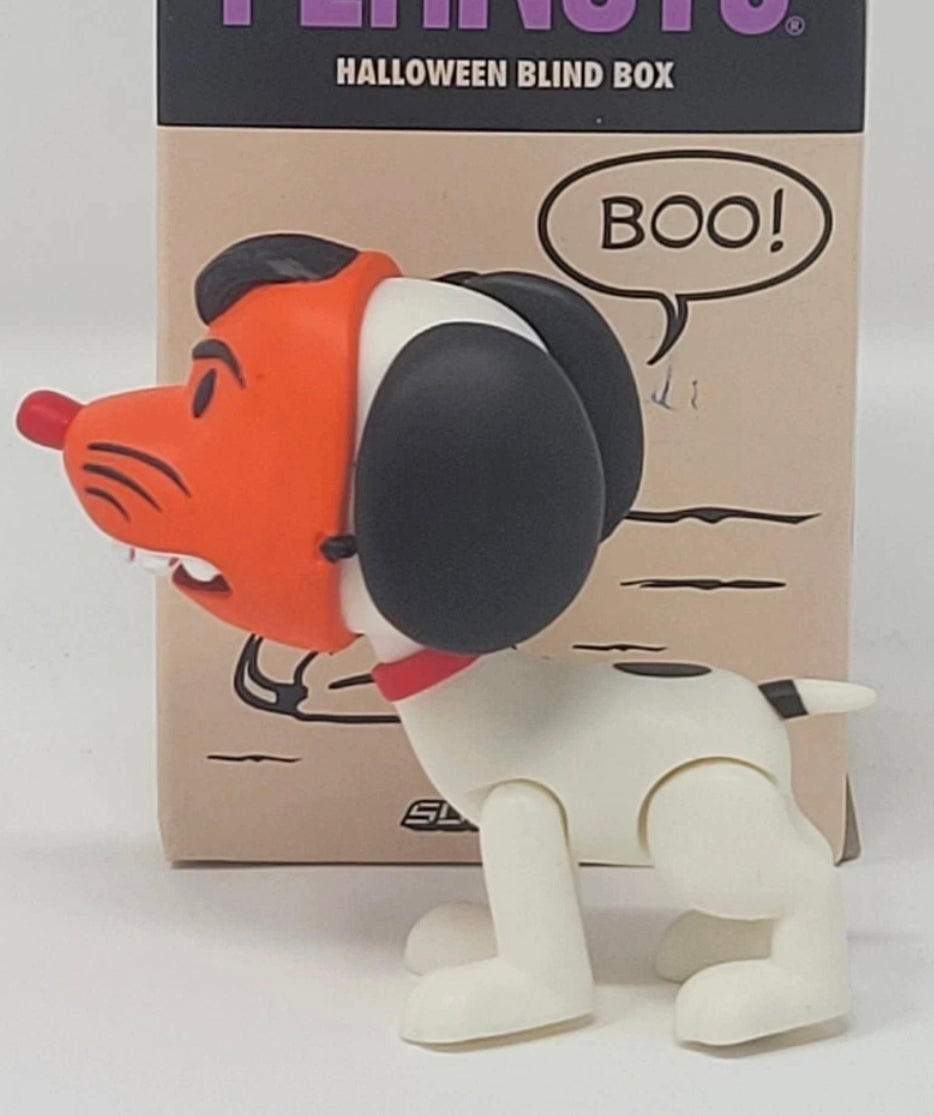 Orange-masked dog Halloween blind box figure standing in front of tan cardboard packaging