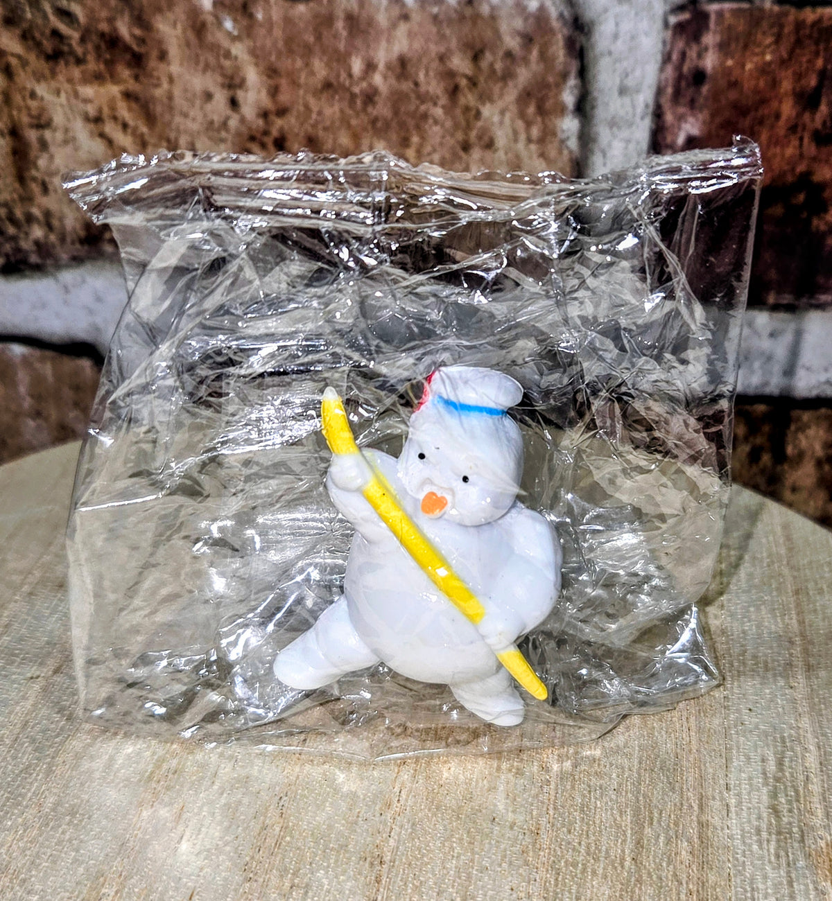 White mini figure in clear bag, blue bib, holding yellow wand