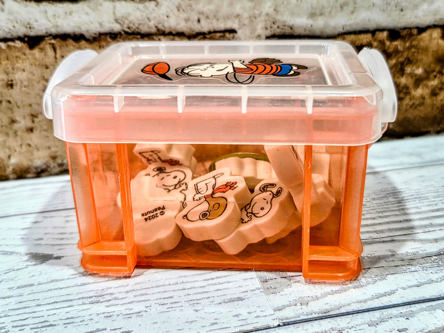 Orange desktop organizer box with Snoopy erasers visible inside