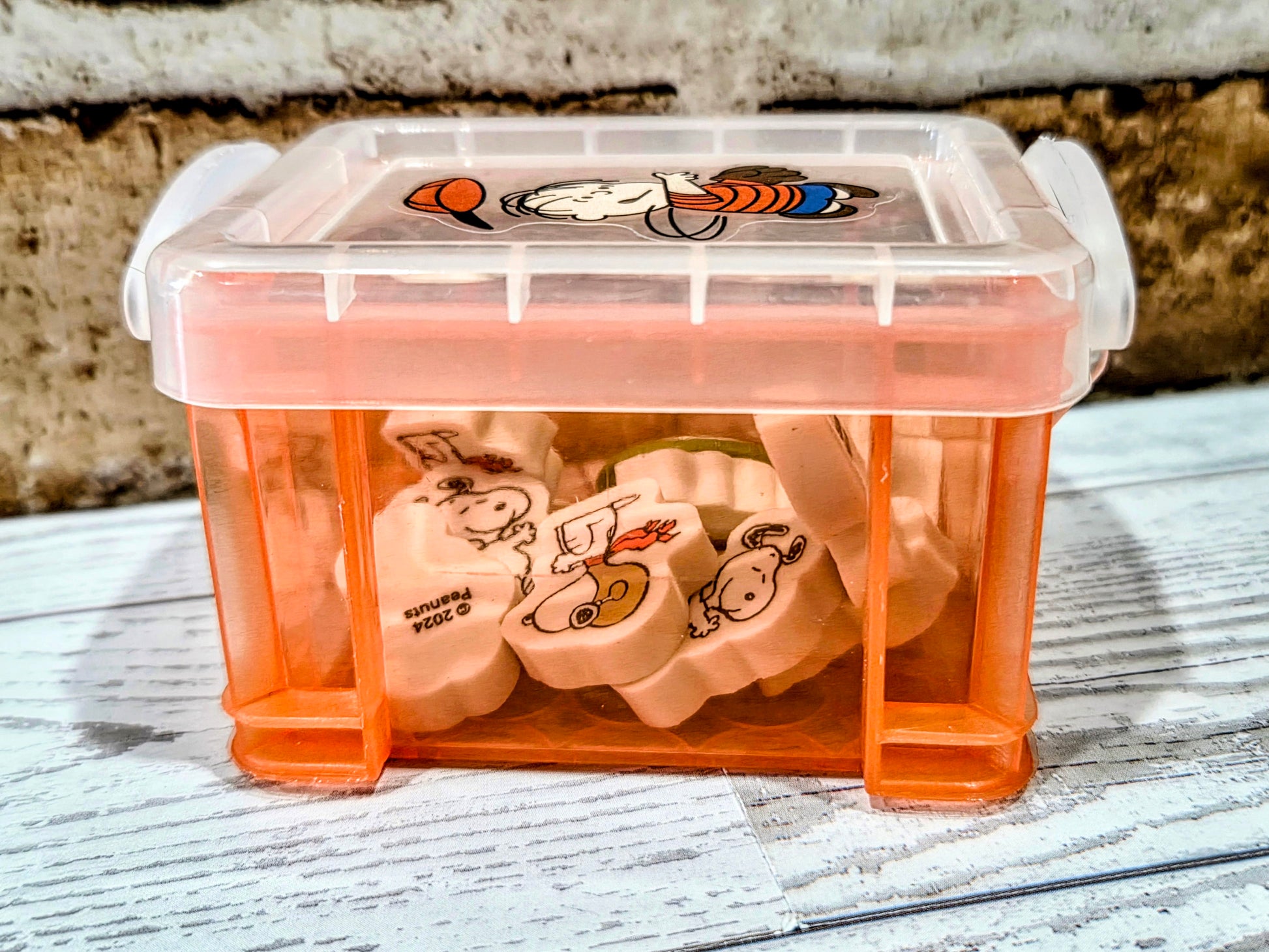 Orange desktop organizer box with Snoopy erasers visible inside