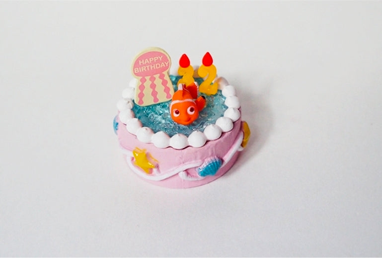 Birthday ocean cake mini figure with clownfish in blue water, candles, and “Happy Birthday” sign