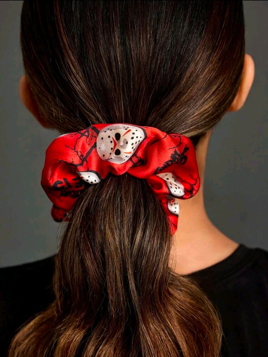 Red and black satin scrunchie with Jason-style mask print, on brown hair ponytail