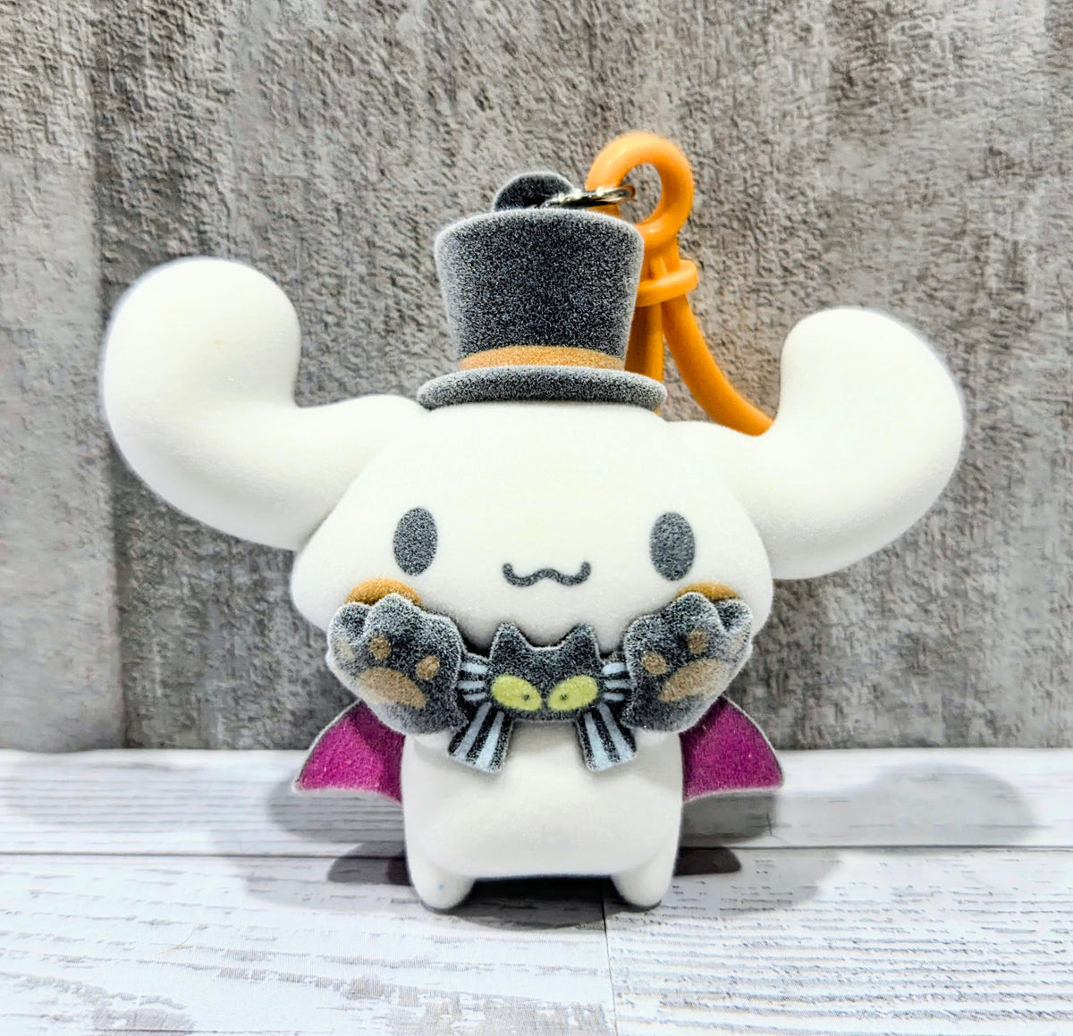 Flocked Cinnamoroll bag clip with orange loop, gray top hat, and bow detail