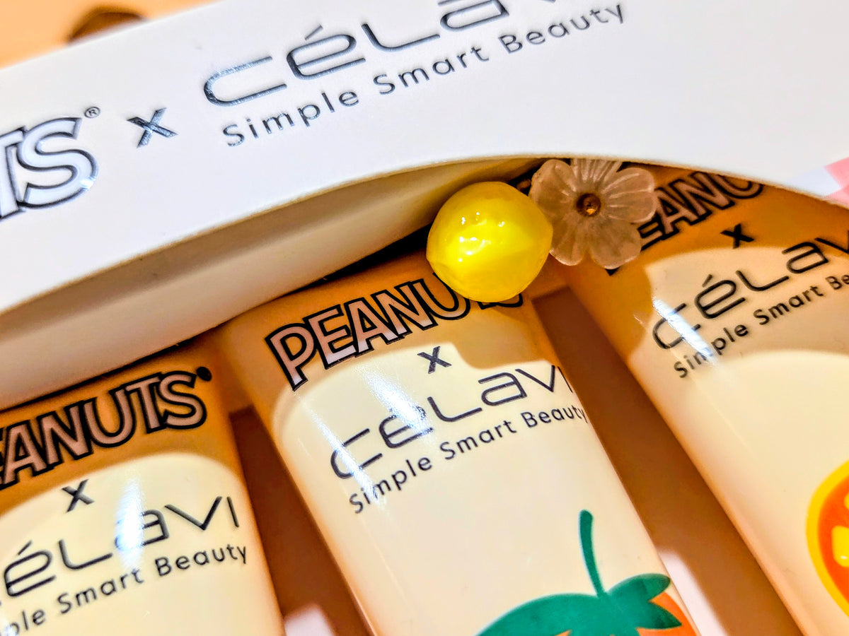 Close-up of fruit lip gloss tubes in box with PEANUTS and celavi branding