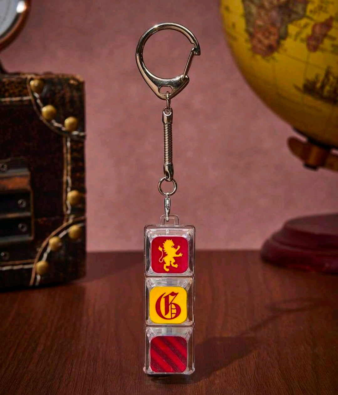 Metal spring keychain with three stacked clear keycaps: lion, yellow crest, red stripes
