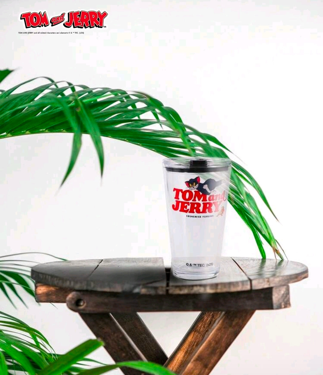 Clear tumbler with Tom and Jerry graphic and black lid on round tray