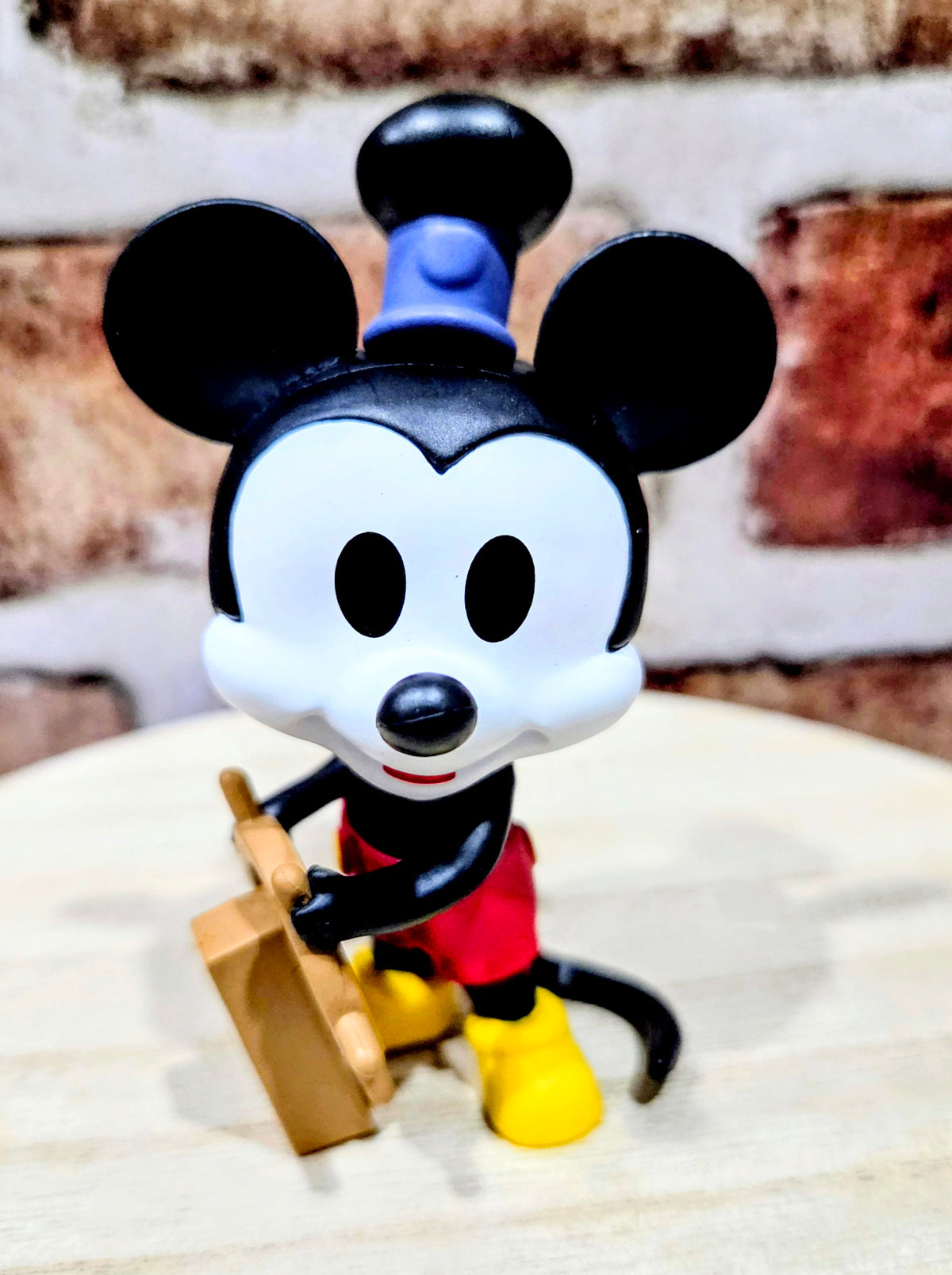 Mickey Mouse mini vinyl figure holding a tan box-like prop, blue collar detail