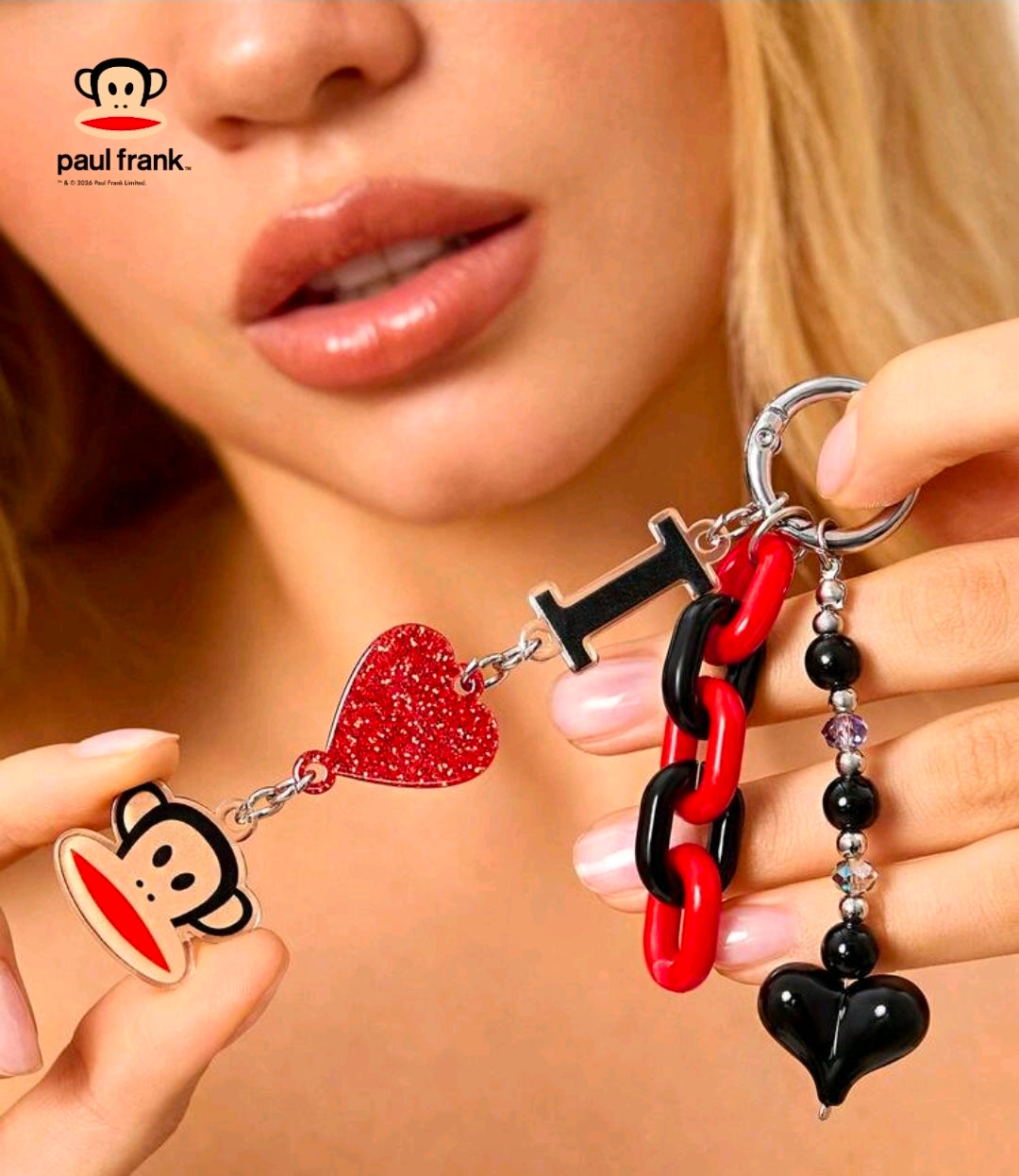 Red and black chain keychain with glitter heart and monkey face charm held in hand