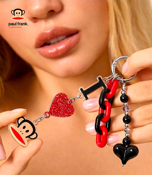 Red and black chain keychain with glitter heart and monkey face charm held in hand