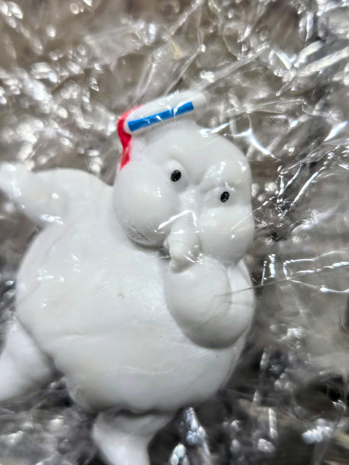 White mini Puft figure sitting with red-and-blue striped hat, smiling face.