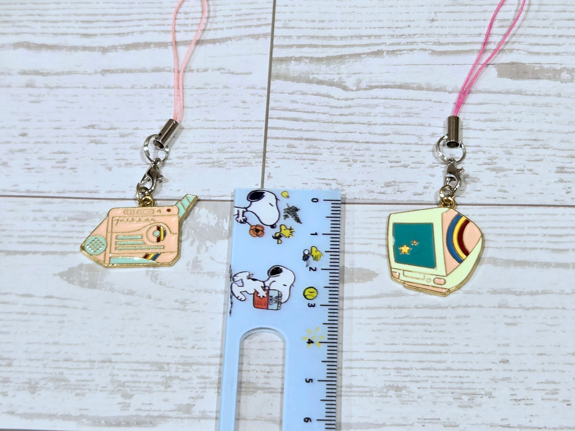 Pair of retro phone charms with pink lanyard cords, shown beside a measuring ruler