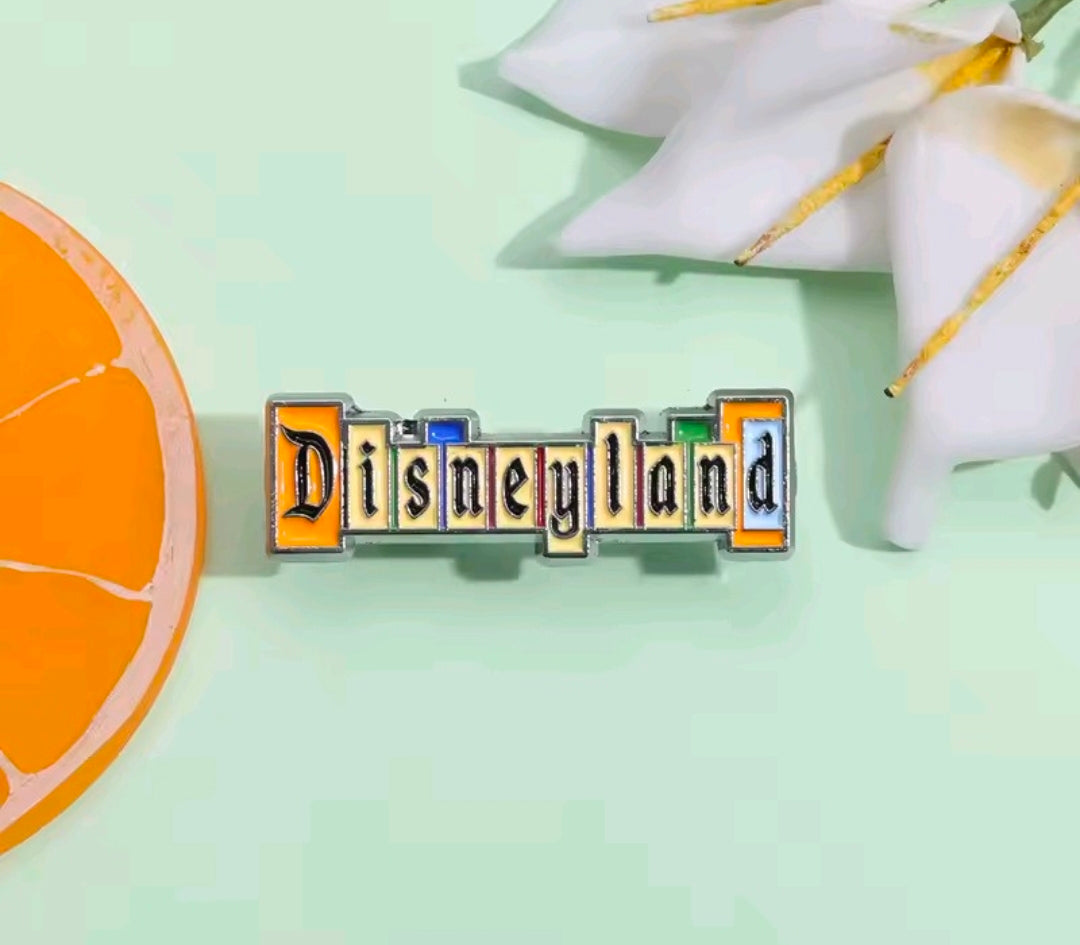 Enamel pin with DisneyLand logo, orange and blue enamel letters on dark border.