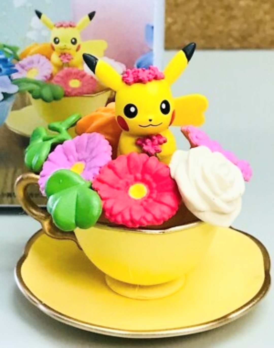 Yellow Pikachu mini figure in yellow teacup with pink and green flowers on plate