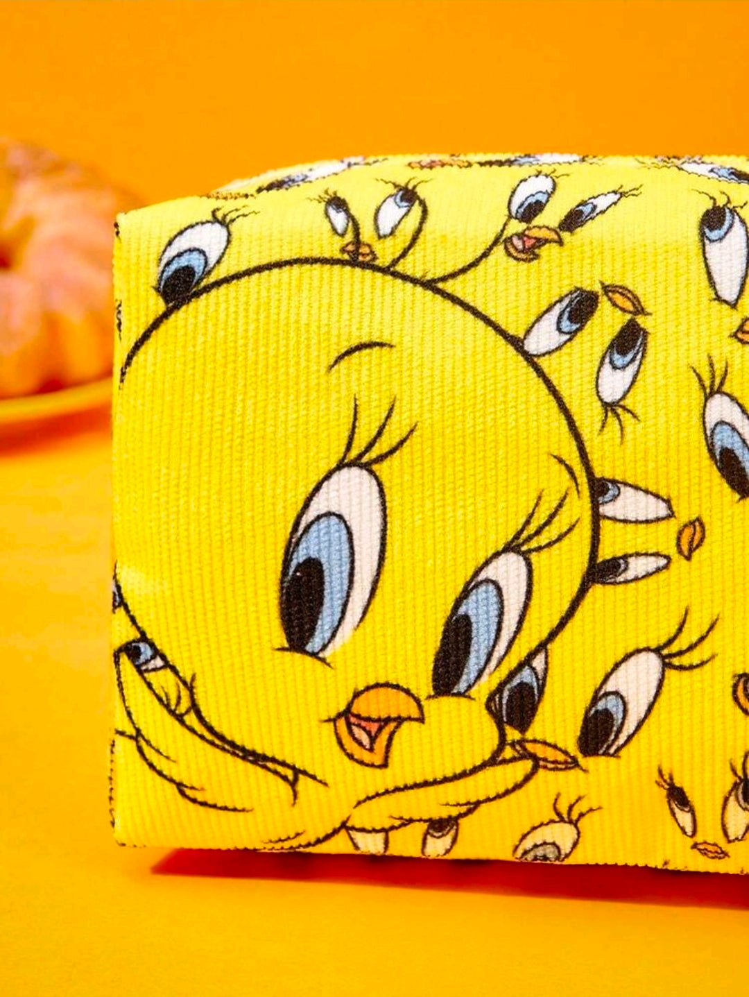 Yellow makeup bag with repeating Tweety face print and zip closure