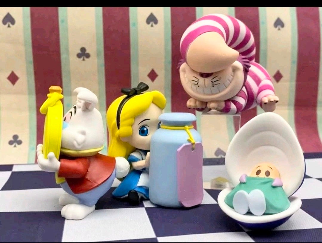 Four gashapon figures posed on a checkered board, with teapot and striped cat