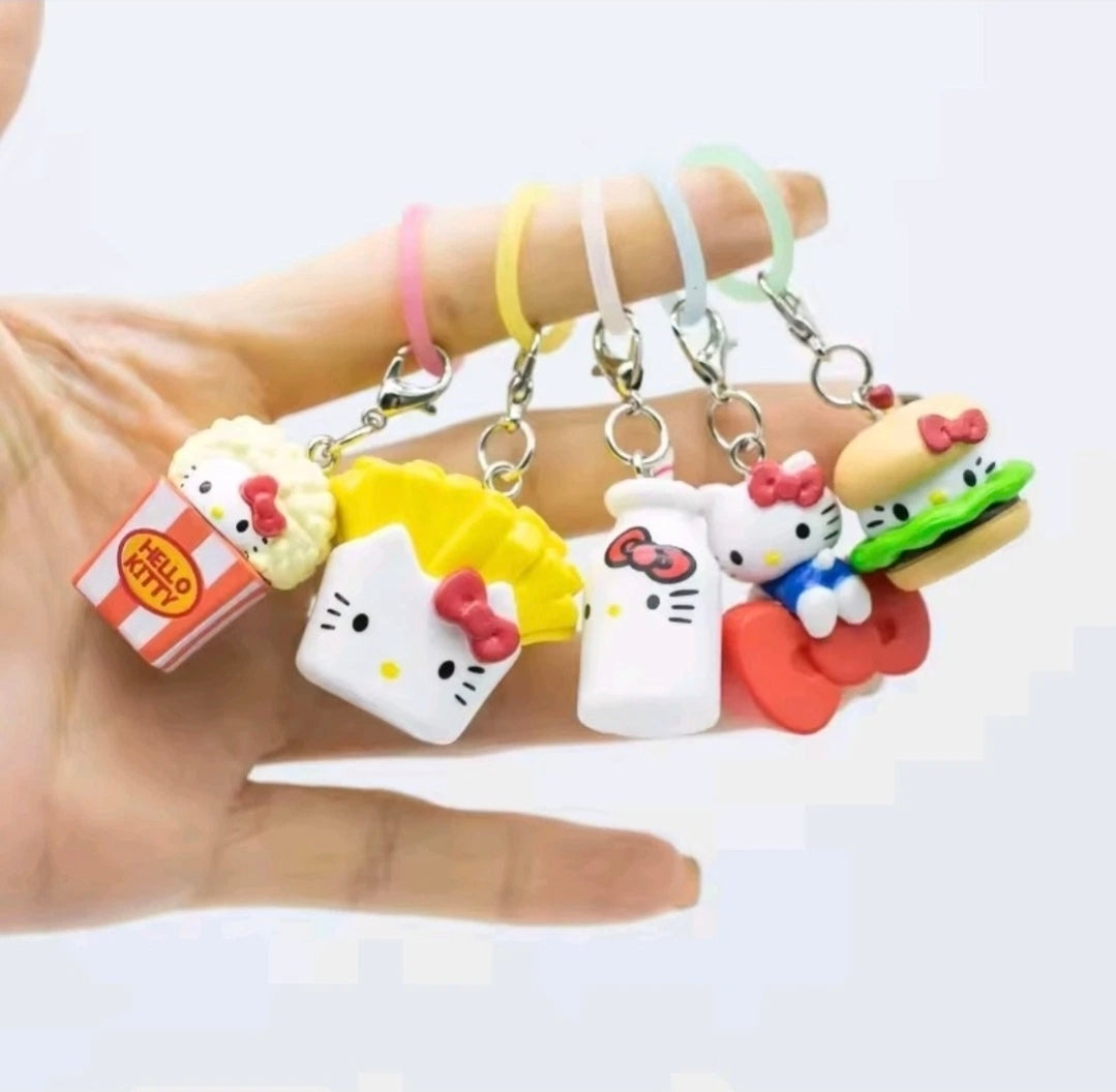 Five Hello Kitty food-themed keychains with metal clasp rings, held in a hand