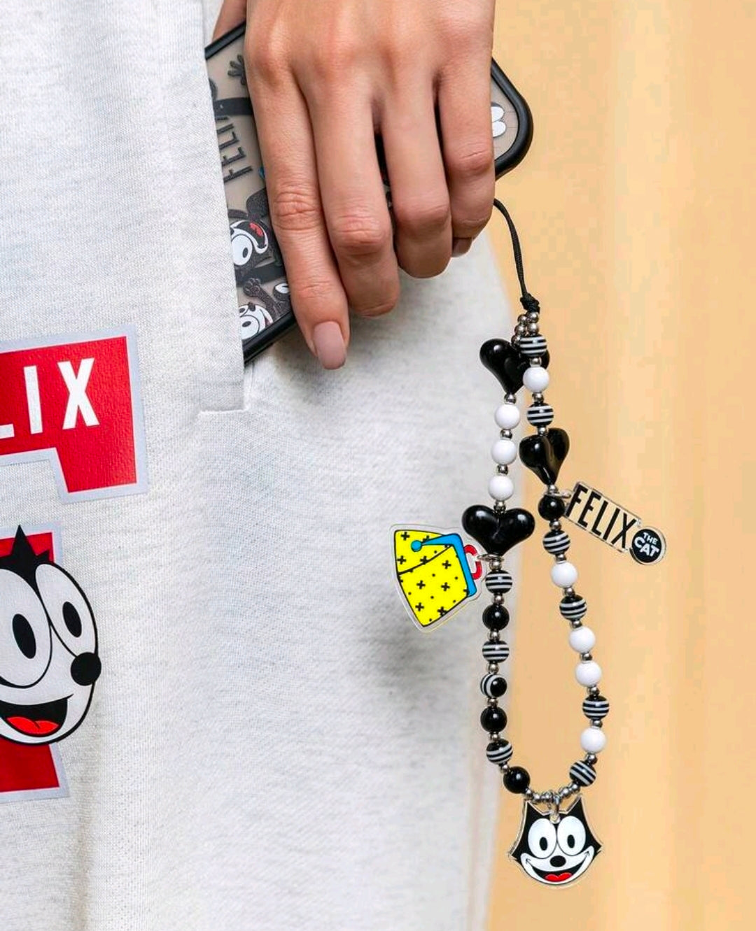 Black and white beaded phone charm lanyard with Felix face charm and yellow heart charm