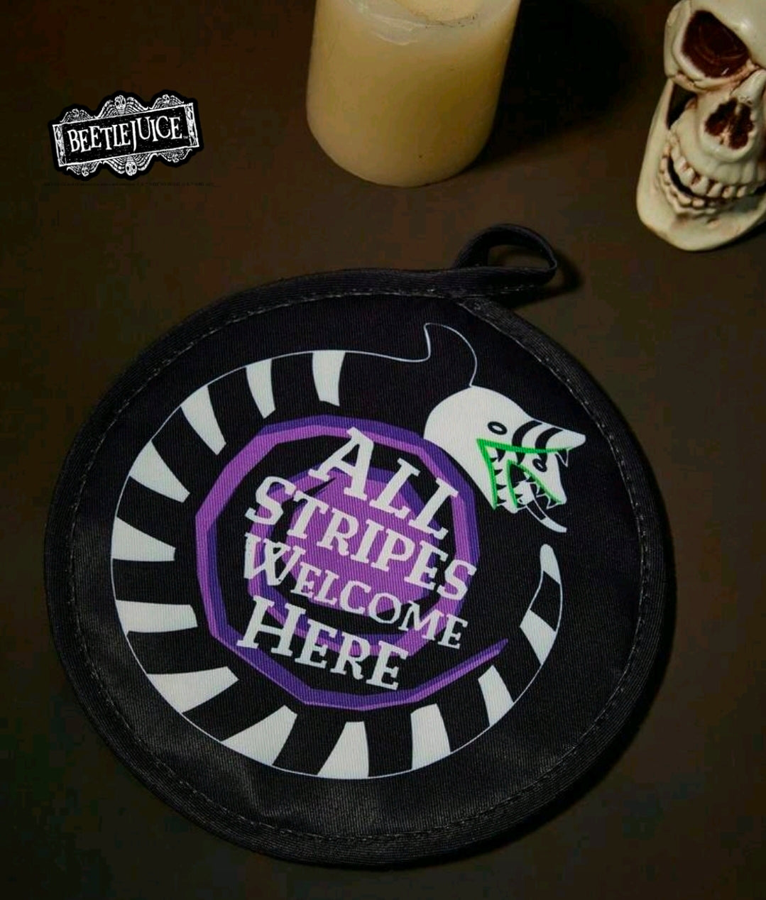 Round pot holder with purple “All Stripes Welcome Here” text and green bug graphic
