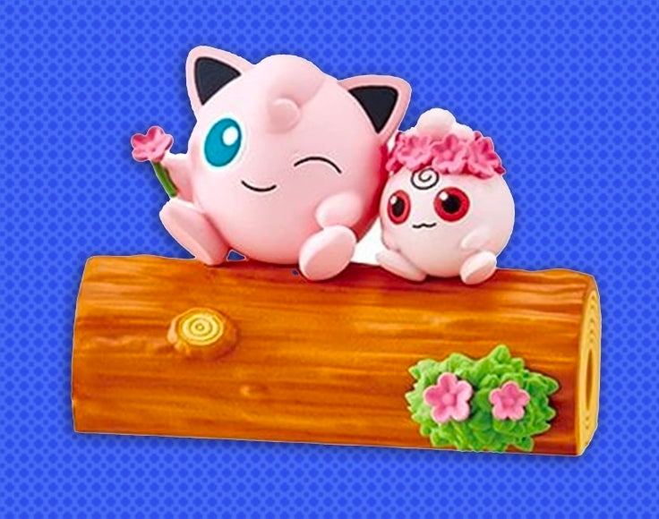 Pink Jigglypuff and small Igglybuff toy figures resting on a brown log.