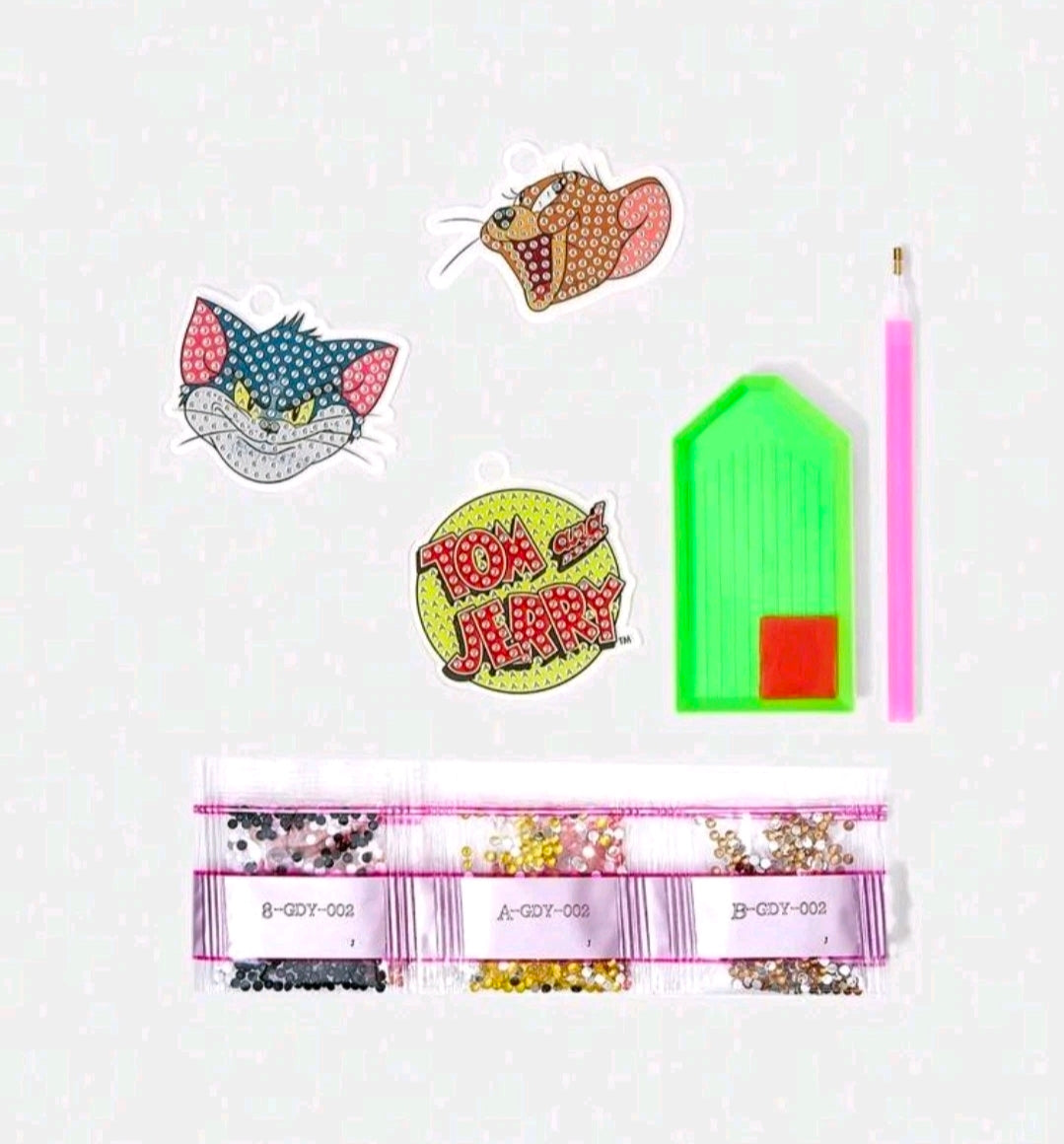 Diamond painting keychain kit pieces and tools: charms, bead strands, green tray, pink stylus