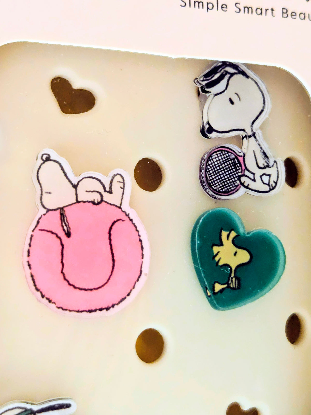 Illustrated hair charm set on packaging insert with pink, teal, and Snoopy charms