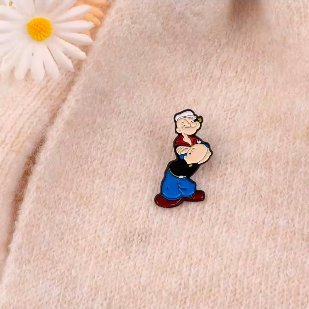 Cartoon sailor enamel lapel pin, small standing figure with red collar and blue pants.