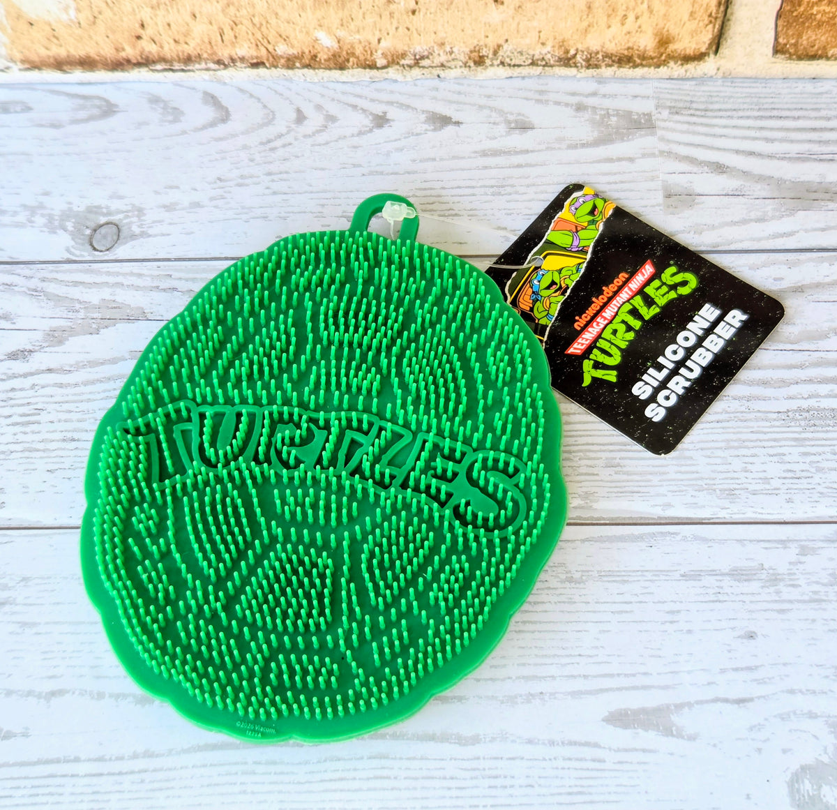 Green TMNT silicone scrubber pad with Teenage Mutant Ninja Turtles logo