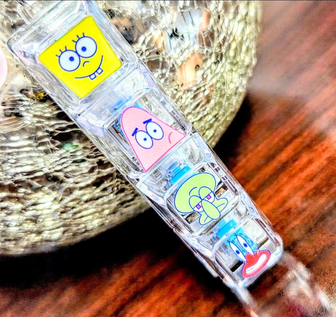 Clear acrylic keyboard fidget keychain angled view with four SpongeBob-themed character faces