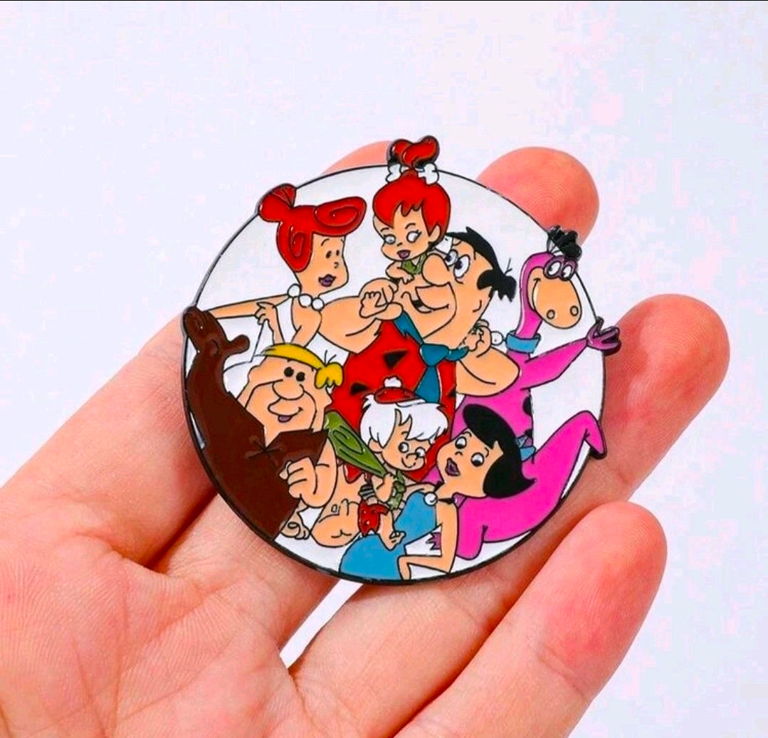 Round enamel pin brooch with The Flintstones family cartoon scene, held in palm