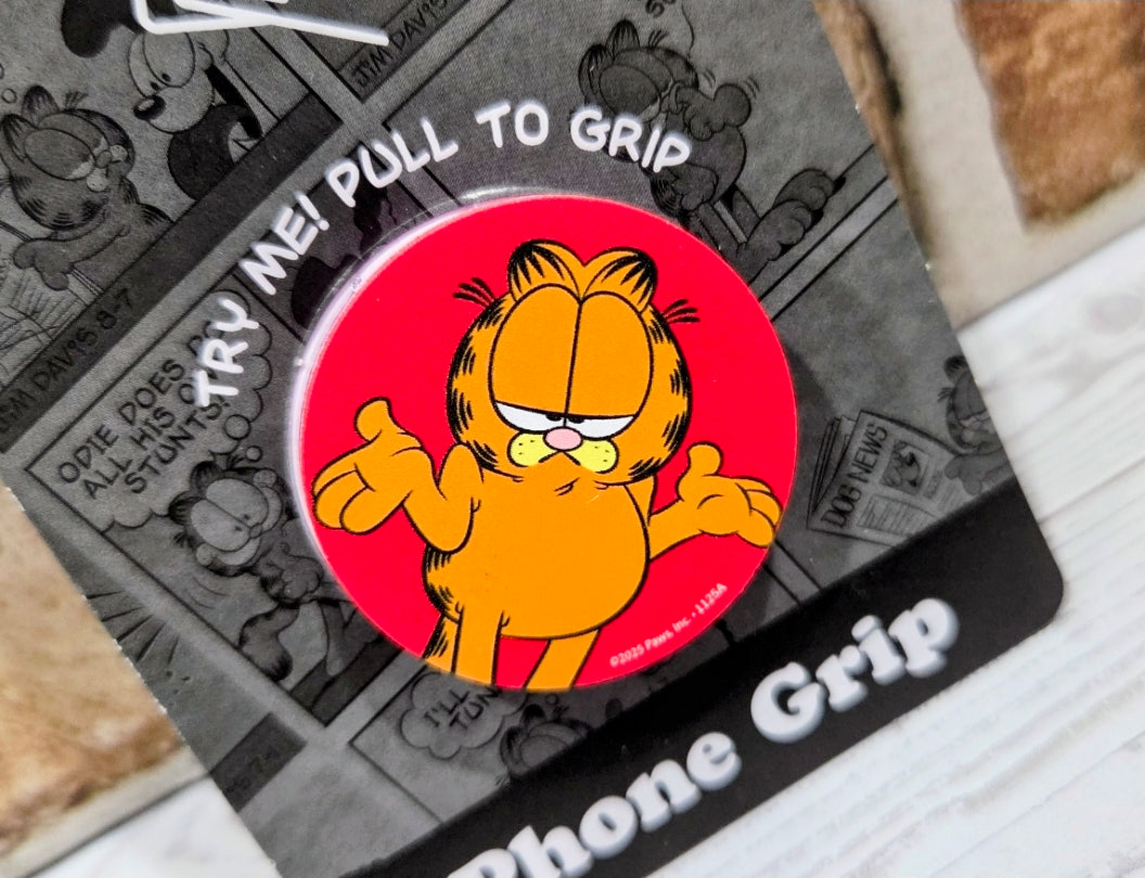Garfield phone grip holder close-up: red circle with Garfield character and white pull tab.