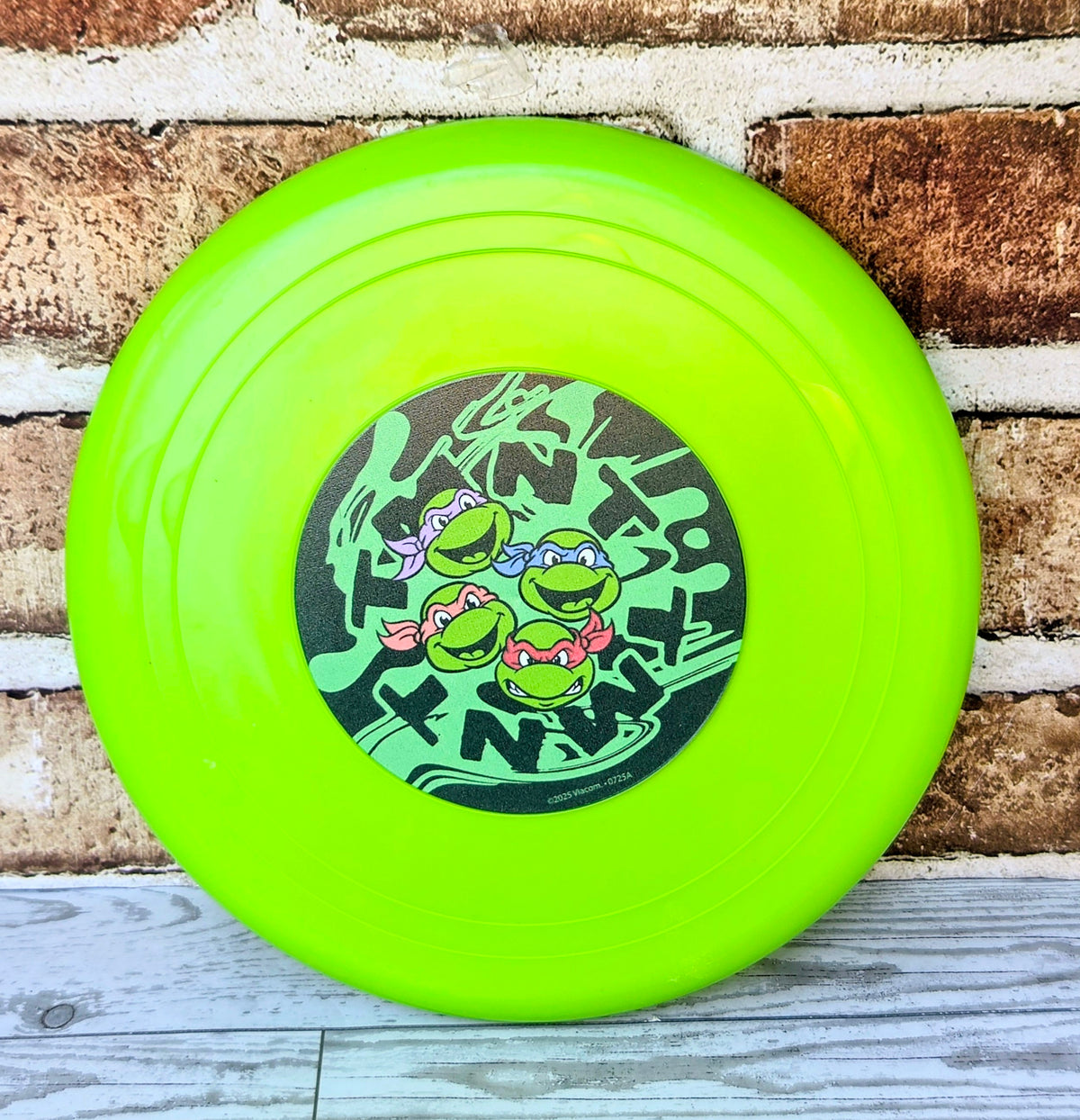 Neon green frisbee with circular TMNT graphic in the center