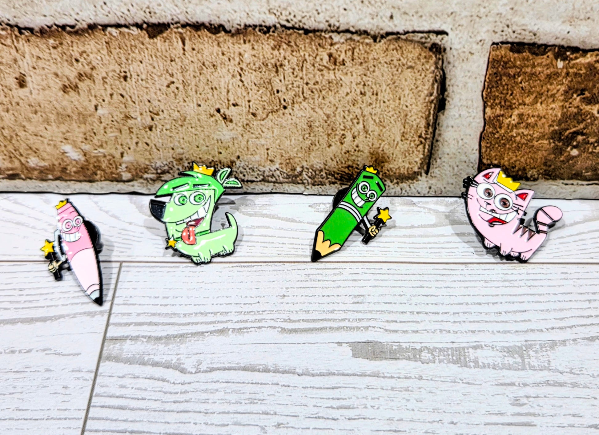 Enamel character pins set laid out on a light surface, four designs visible