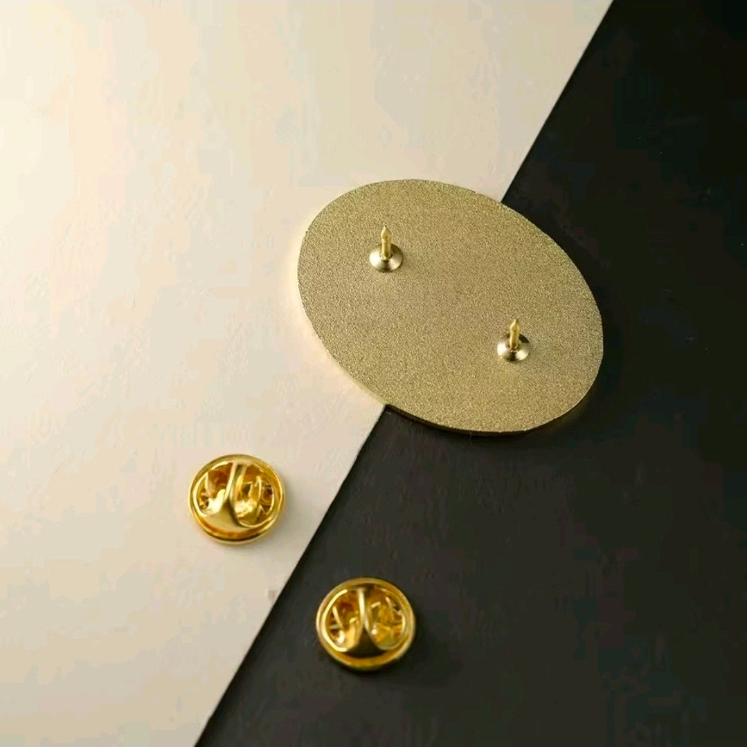 Gold-tone pin backs with butterfly clasps on light and dark surfaces.