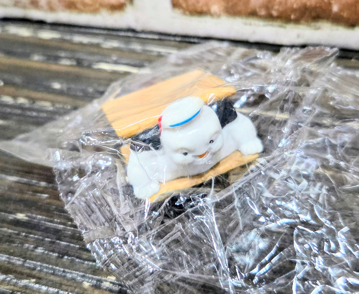 Toy mini figure on graham cracker with dark chocolate piece, sealed in clear plastic bag