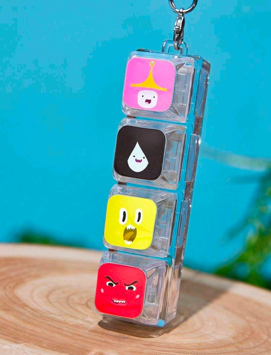 Clear stacked cube keychain with pink, black, yellow, and red character faces