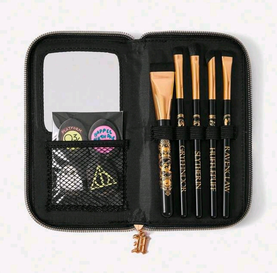 Open black zippered brush case with gold-handled brushes, mirror panel, and accessory pocket