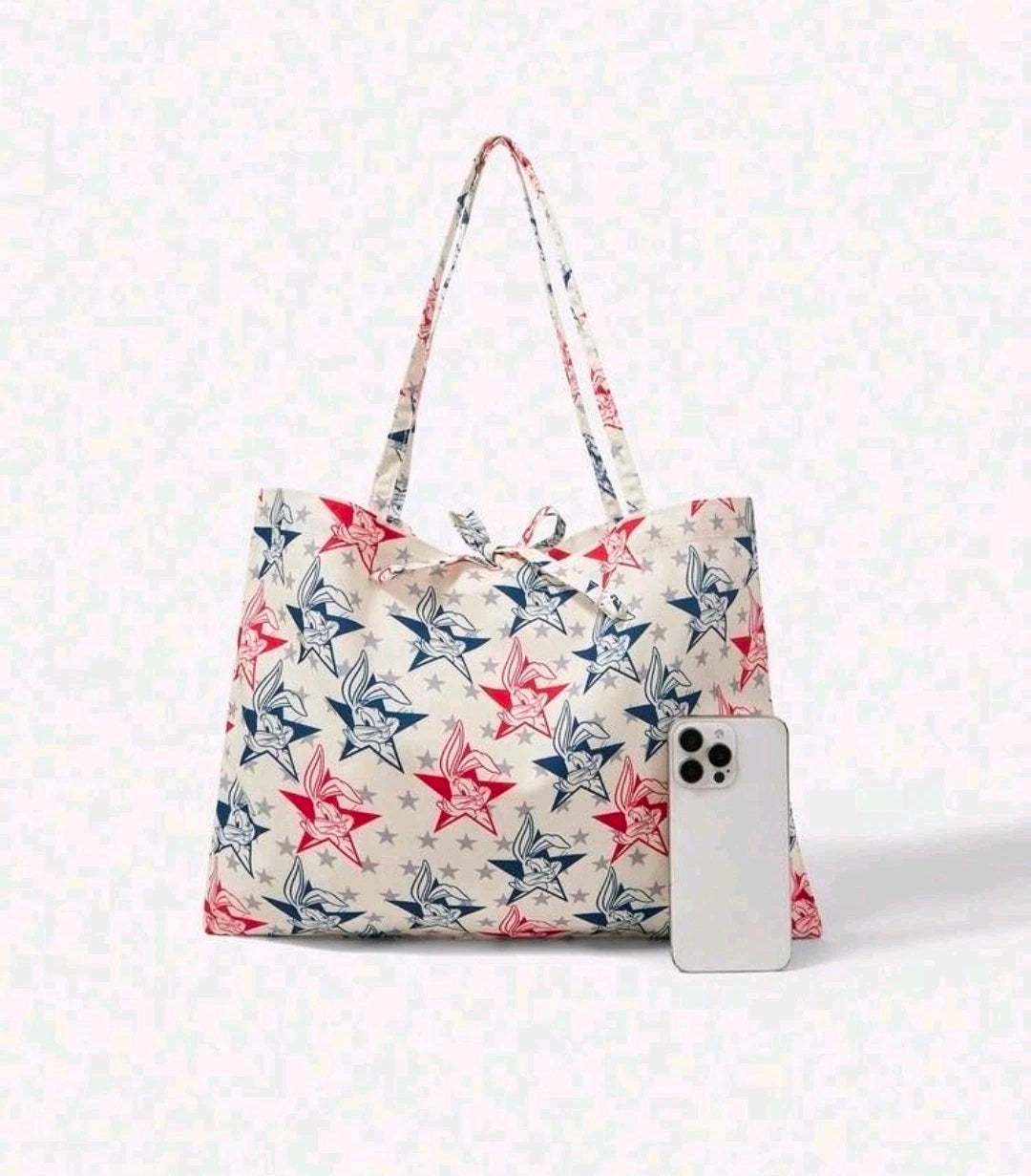 Patriotic tote bag with star and bunny print, shown with a white smartphone