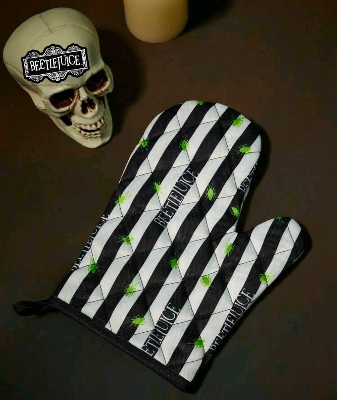 Black-and-white striped oven mitt with green bug print and Beetlejuice branding